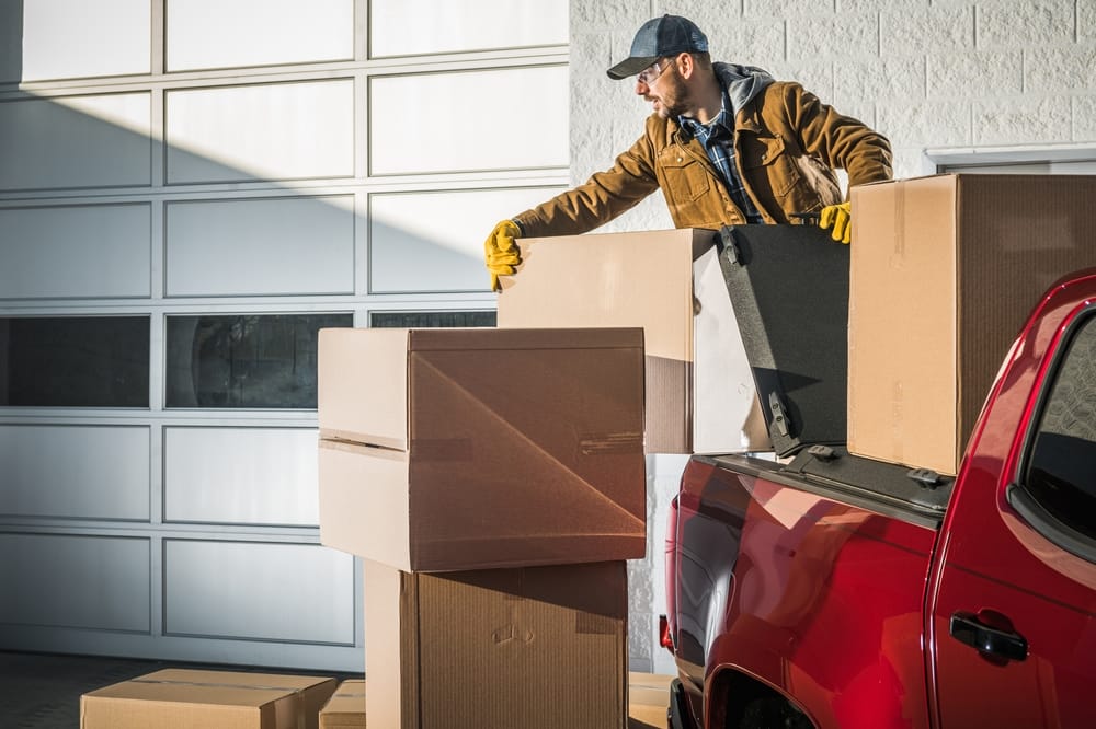 Man unloading a red pick up truck, indicative of making money with his pick up