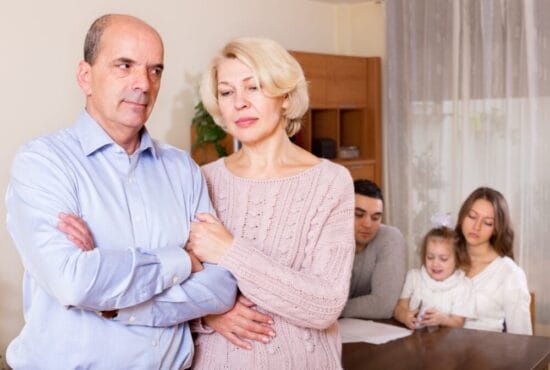 Older couple in the foreground looking unhappy while a younger man and woman with a small child are in the background