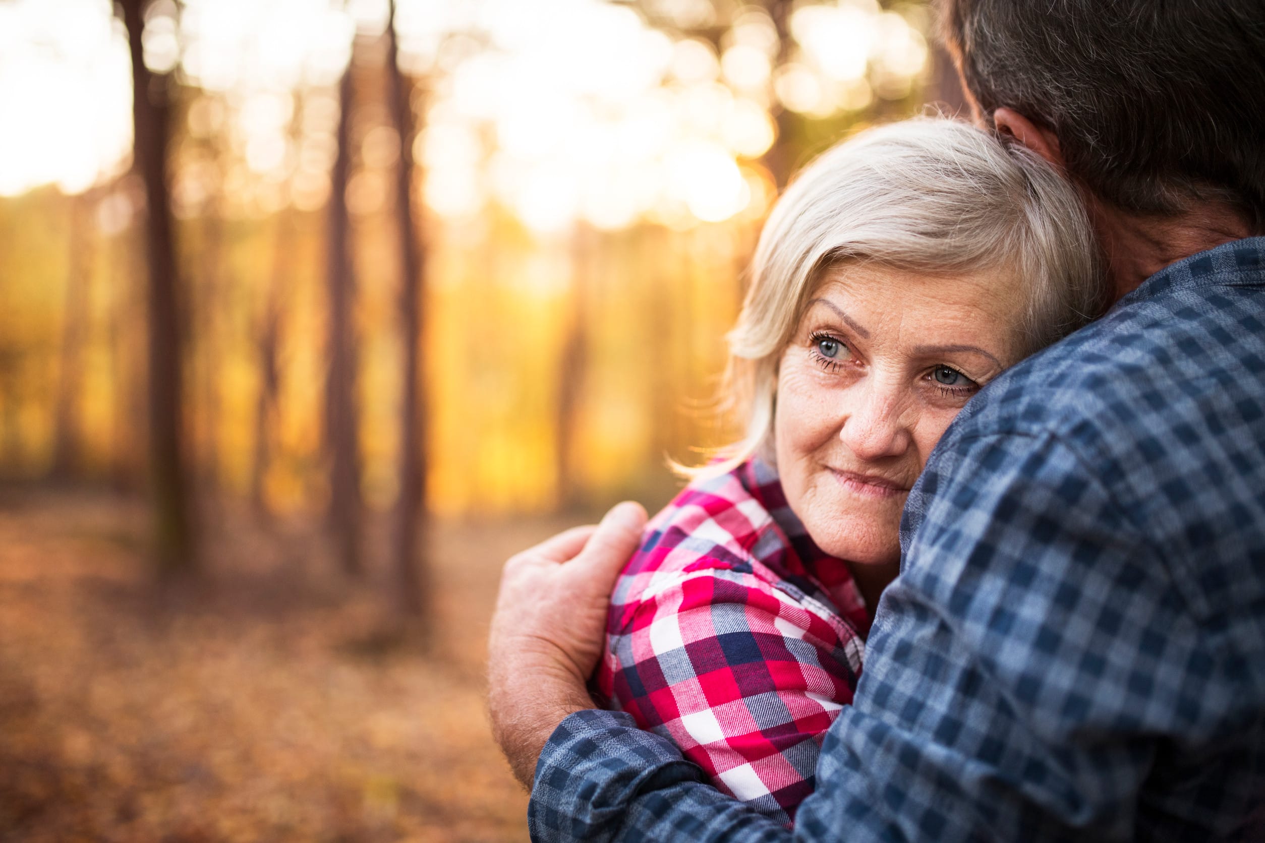 Active senior couple on a walk in a beautiful autumn forest. Unrecognizable man and woman hugging.