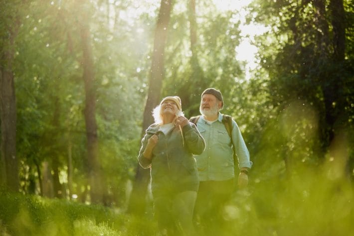 Baby boomer couple walking in the woods, indicative of good cognitive health.